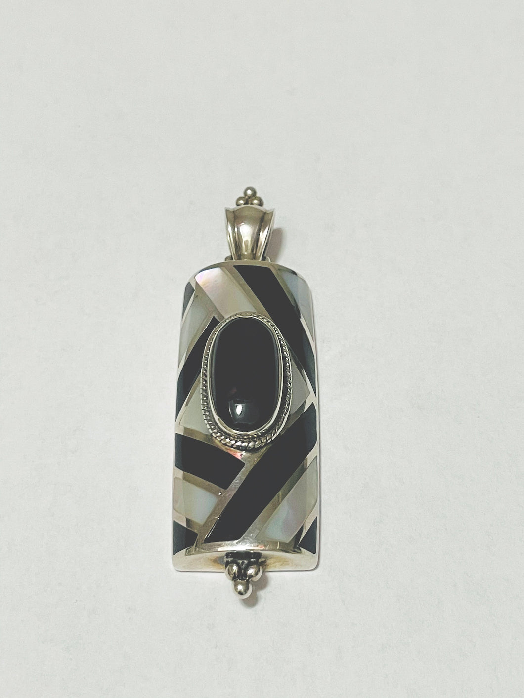 This lovely pendant consists of a lovely Mother of Pearl and Black Onyx design with a large Onyx stone in the middle.  It measures 2.75 X 1.24 inches.  We include a complimentary Sterling Silver chain to complete the over all look.